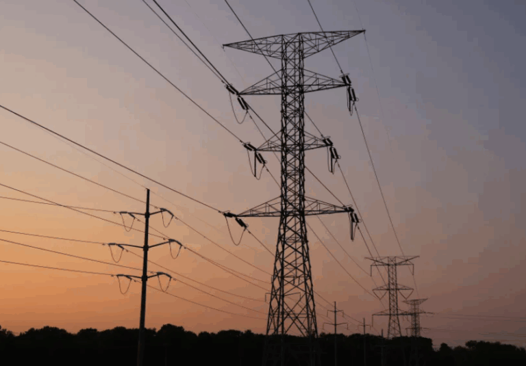 A row of ComEd high-voltage transmission lines at sunset, representing Illinois electrical grid demand and infrastructure.